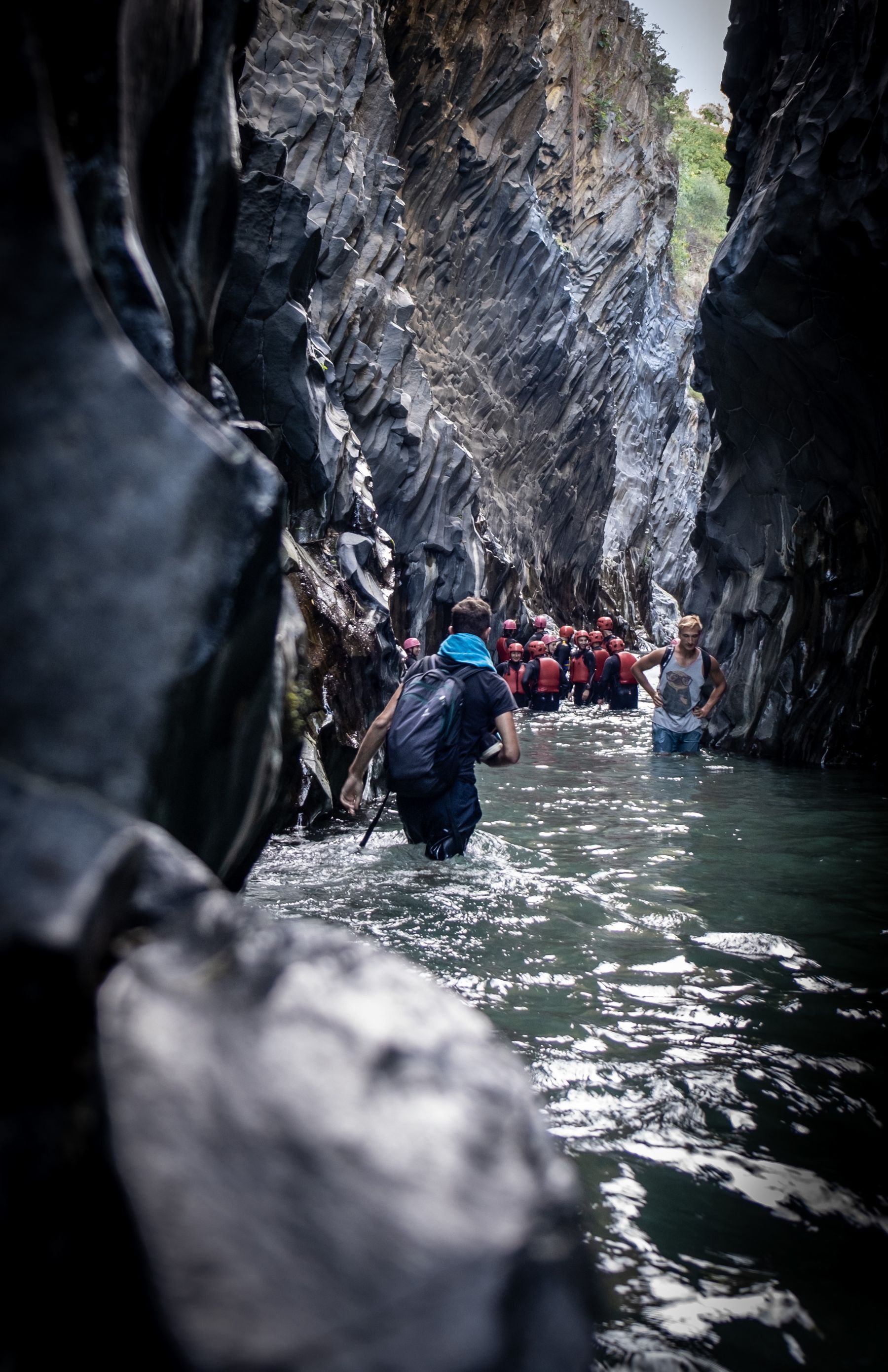 Visitors walking between the dark basalt walls of the Alcantara Gorge