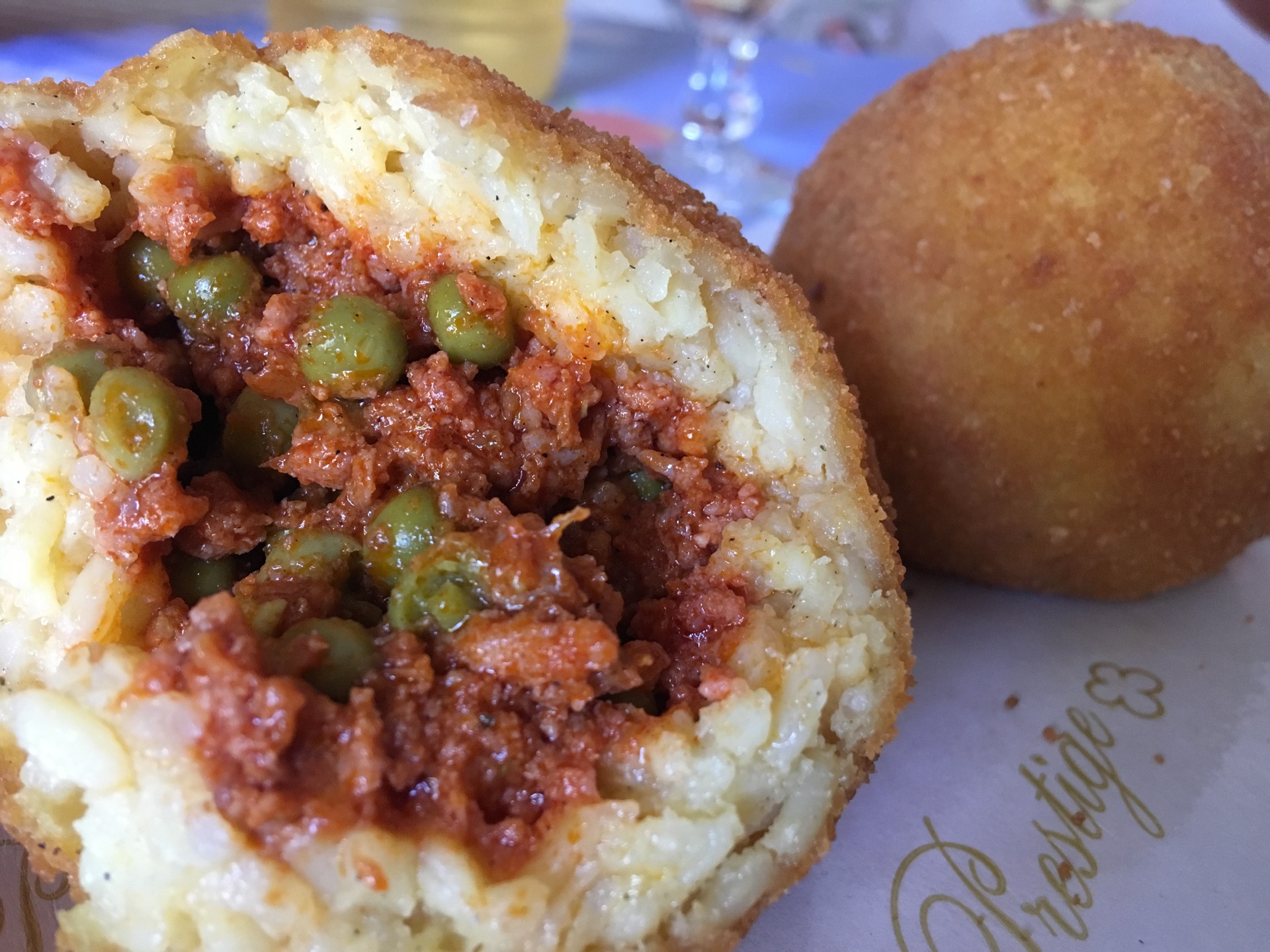 An opened Sicilian arancino with rice, ragù and peas