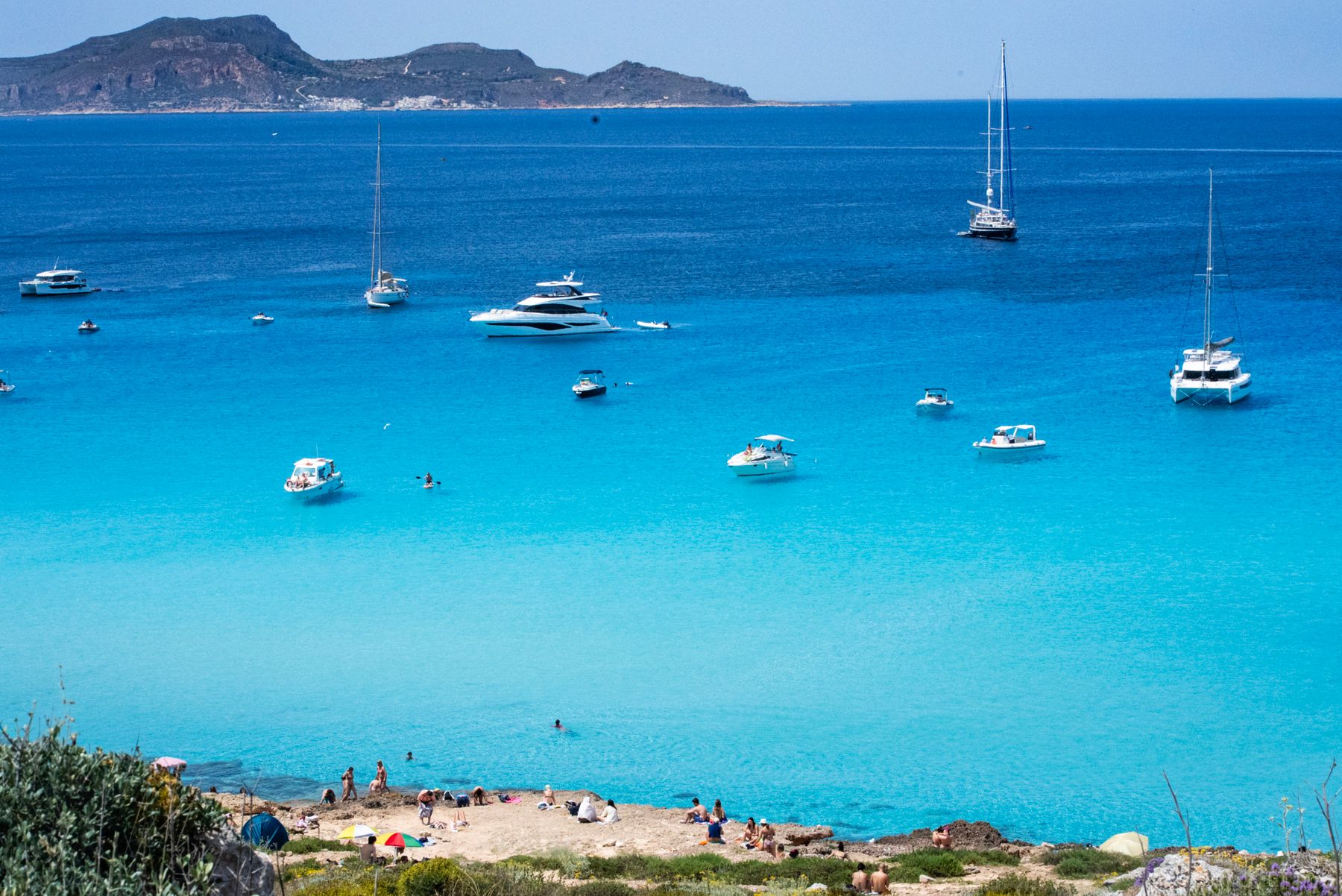 Turquoise water, rocky coast and boats at a Sicilian beach