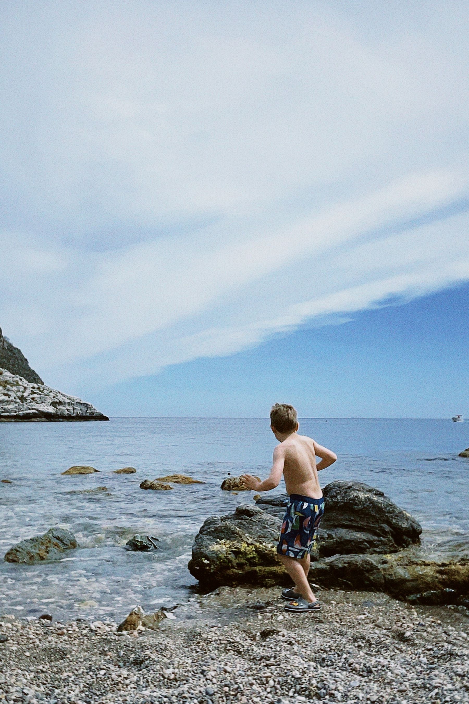 A child playing beside Sicily’s rocky coast
